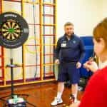 A schoolchild calculating maths whilst playing darts.