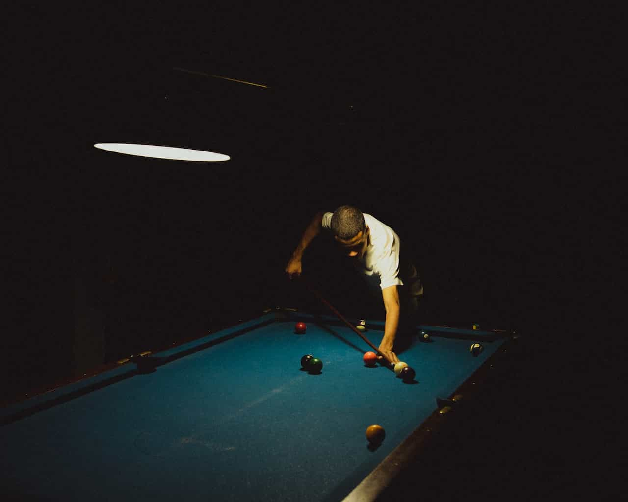 A man playing snooker in a dark room.