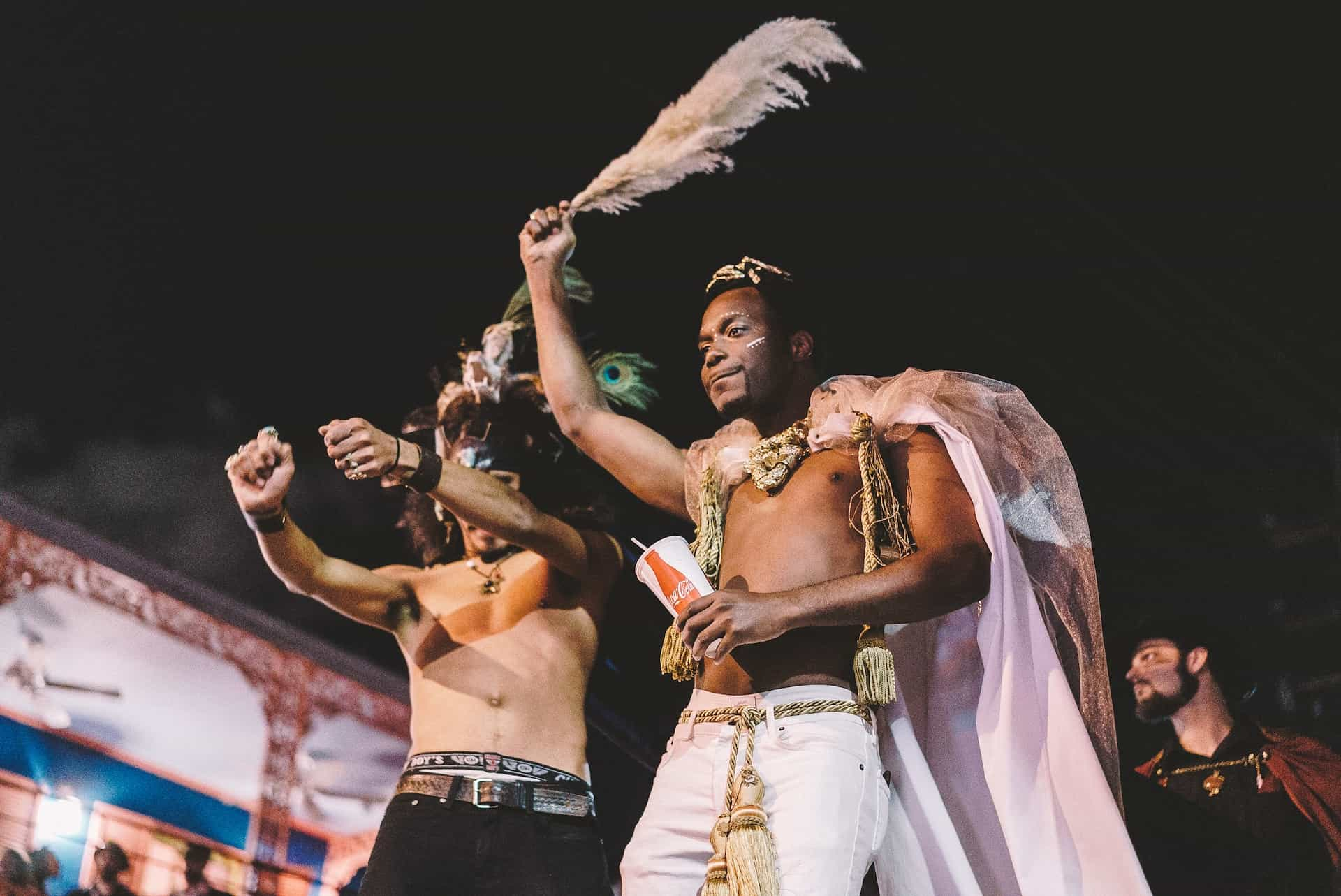 Two men perform topless in makeup at carnival celebrations.