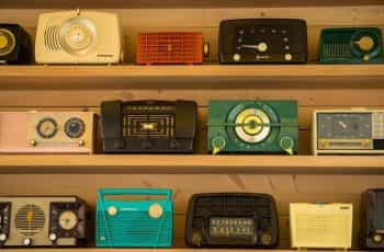 Rows of colorful retro radios sit on wood shelves.