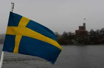 A flag against the sky on the waterfront.