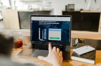 A person sitting in front of a laptop which is displaying an article on how to increase one’s revenue while keeping satisfaction consistent.