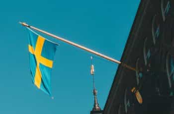 A blue and yellow flag hoisted from a building against a blue sky.