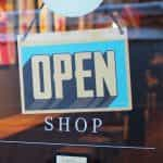 A white and blue OPEN sign on a shop window.